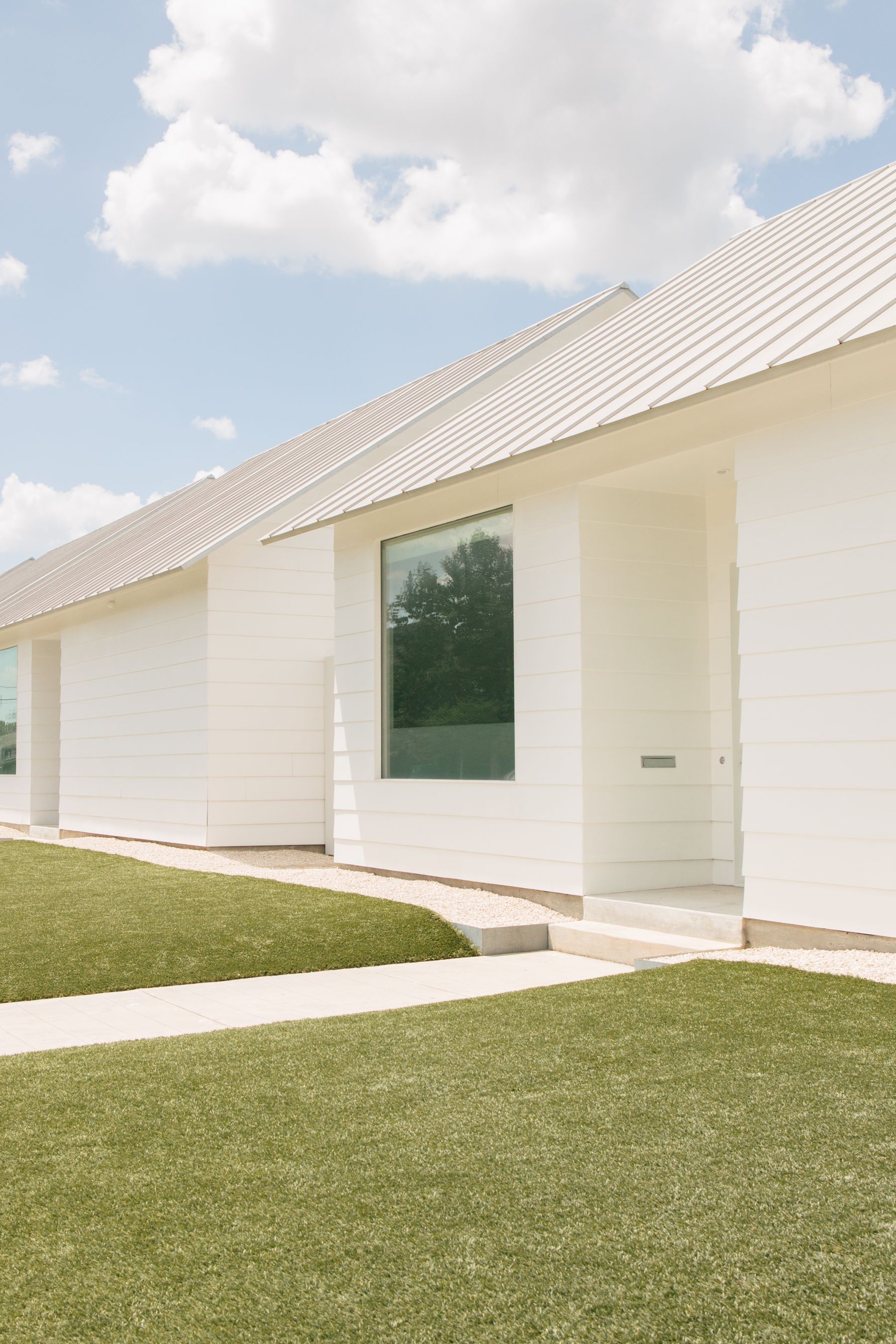 Contemporary Houston home with white siding, tall windows and a front porch